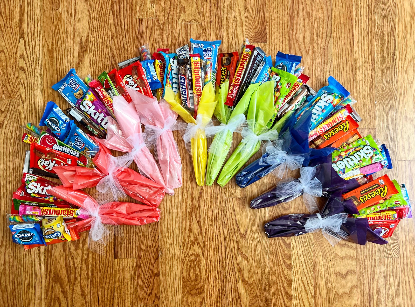 Candy bouquets arranged in a rainbow on a wooden floor