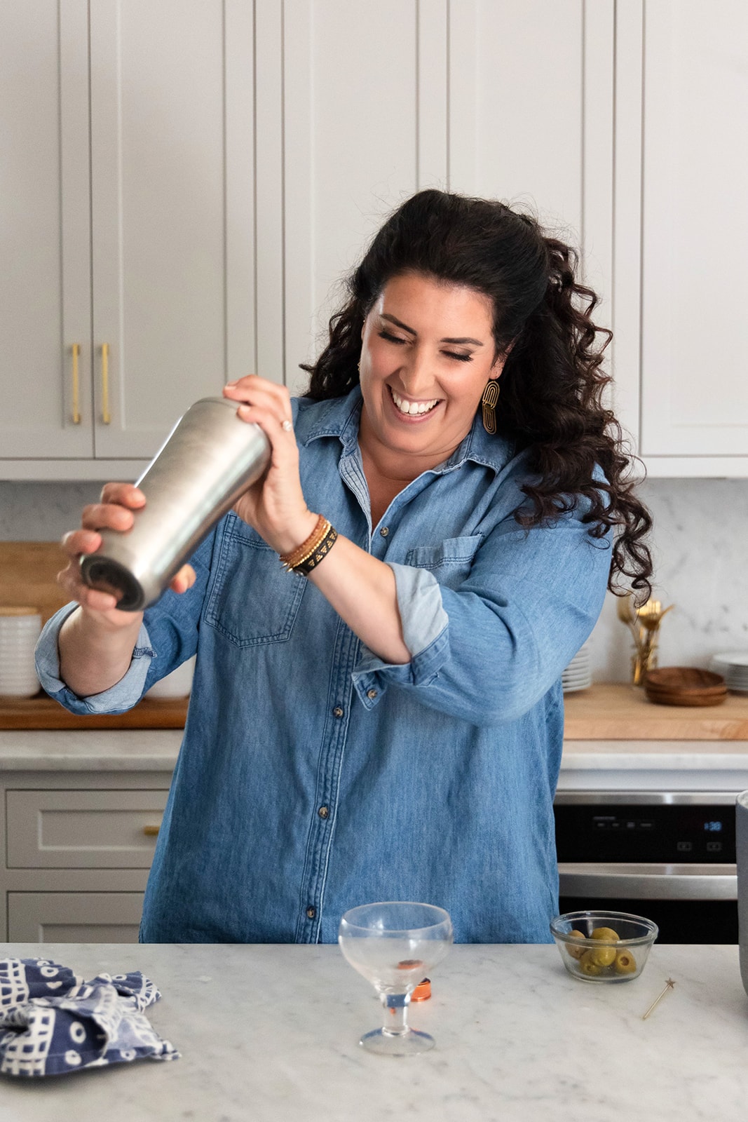 Jeanette laughing as she shakes a cocktail in her kitchen